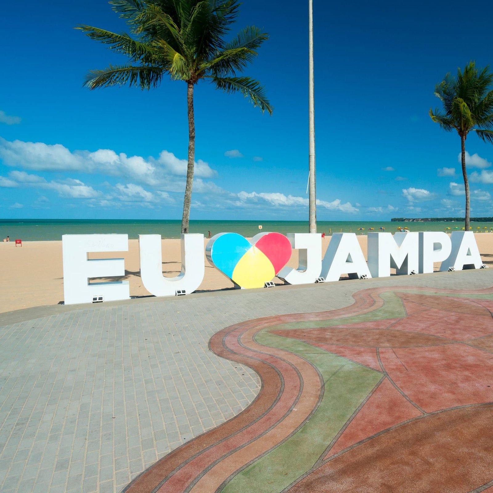 Letreiro Eu amo Jampa na praia de Tambaú, com coqueiros, areia e mar